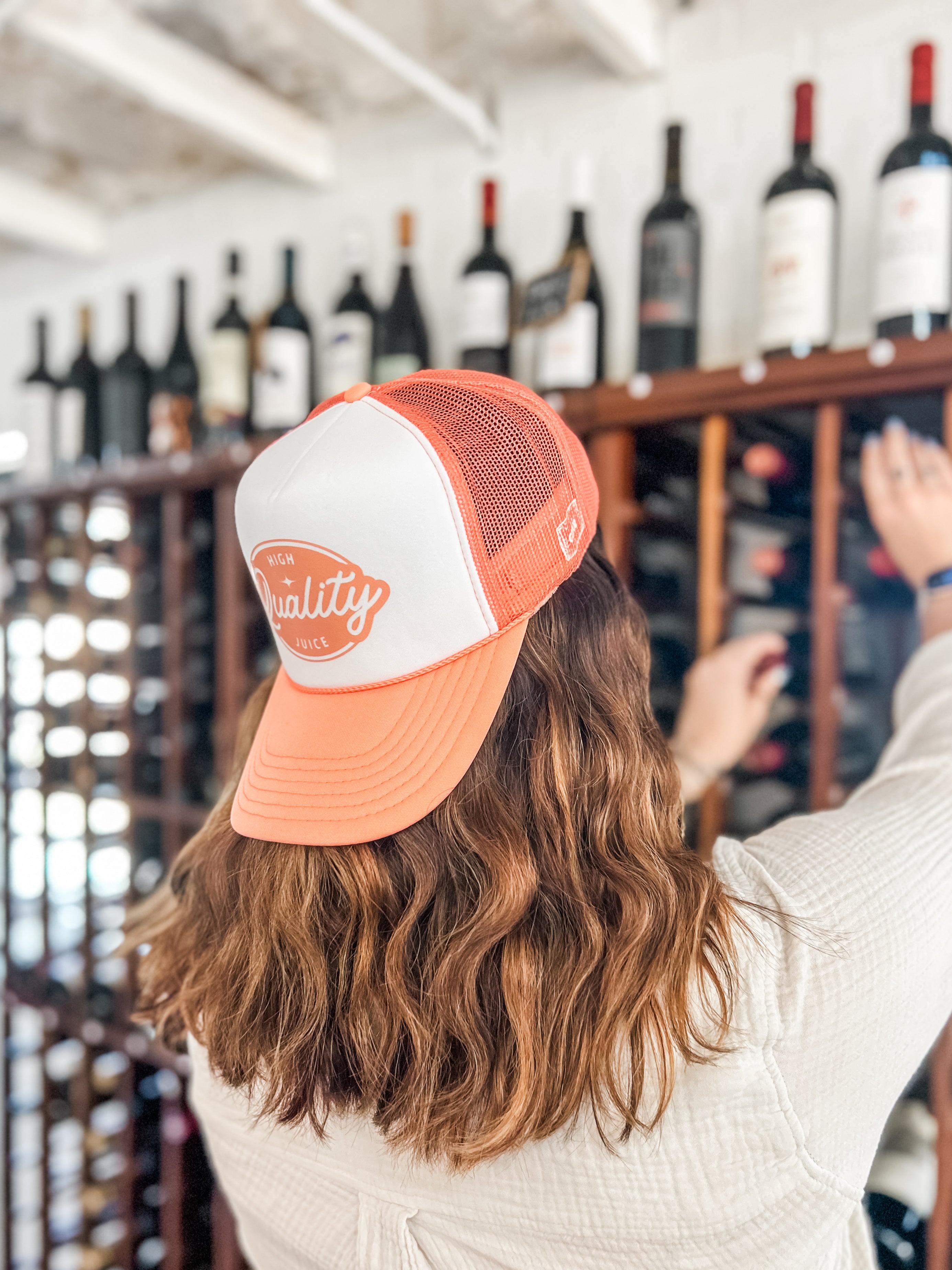 woman wearing an orange and white high quality juice corkie foam cap in a wine cellar